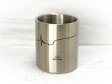 Metalltasse mit aufgedruckter Herzschlaglinie und Logo Alpensonne
