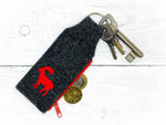 Grauer Schlüsselanhänger mit rotem Steinbock und Münzfach
