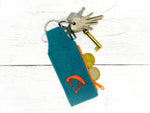 Schlüsselanhänger aus blauem Filz mit orangenen Details, mit Schlüsselbund und Münzen